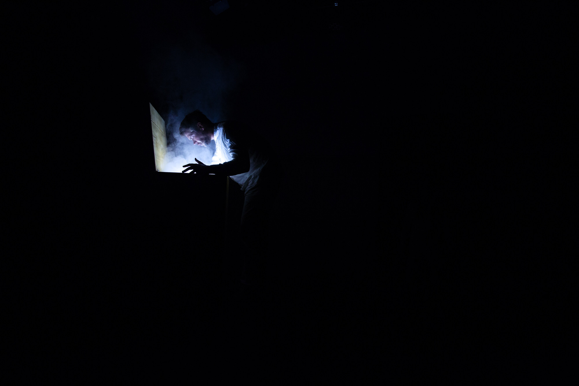 A figure illuminated by a single shaft of light and smoke in Hive Mind